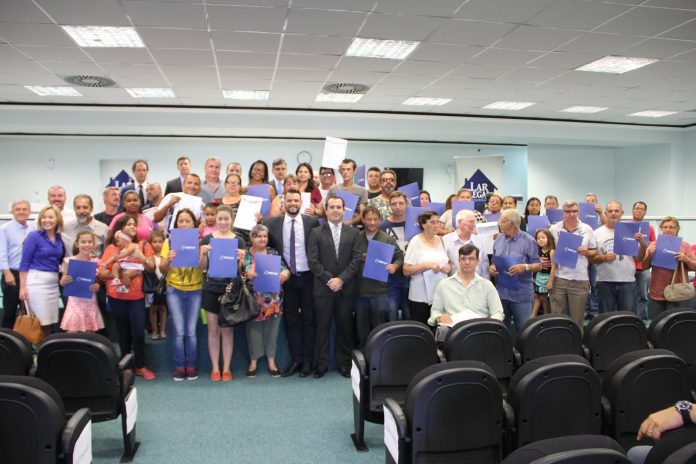 frei Dezenas de pessoas posam com certificados na frente de um auditório