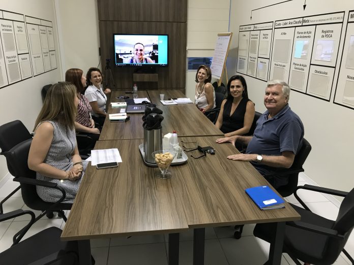 Programa Novos Caminhos Grupo de oito pessoas em uma sala de reuniões, sentado em volta de uma mesa