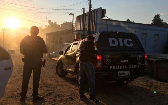 operacao conexao policia civil dois agentes da polícia civil vistos de costas a lado de uma caminhonete com grande inscrição no vidro escrita DIC