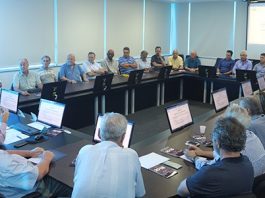 Grande mesa retangular com diversos homens sentados à volta