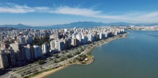 Vista aérea da avenida beira-mar norte, com os prédios ao longo, e o mar e céu azul num dia de sol