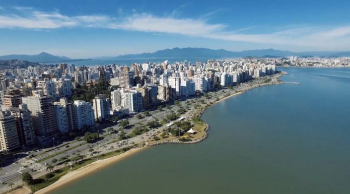 Vista aérea da avenida beira-mar norte, com os prédios ao longo, e o mar e céu azul num dia de sol