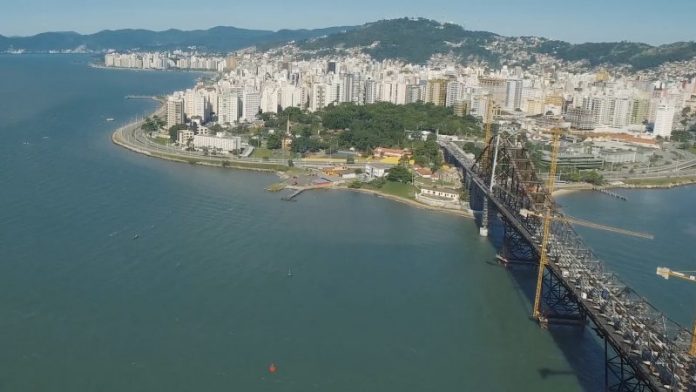 Imagem aérea sobre a Ponte Hercílio Luz mostra o Centro da cidade em destaque