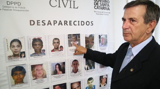 Delagado aponta quadro com diversas fotos de pessoas desaparecidas