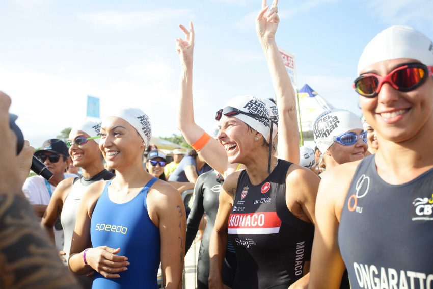 Atletas femininas de maiô de competição comemoram na areia da praia