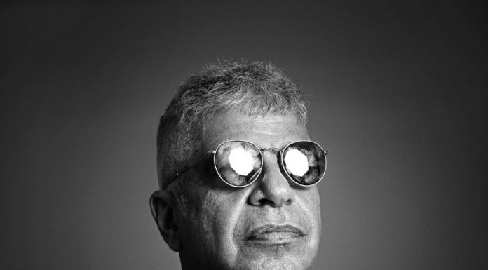Imagem em preto e branco do cantor Lulu Santo usando óculos escuro com o rosto virado para o lado