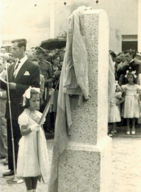 Menina retira pano de monumento em uma praça, com pessoas no entorno