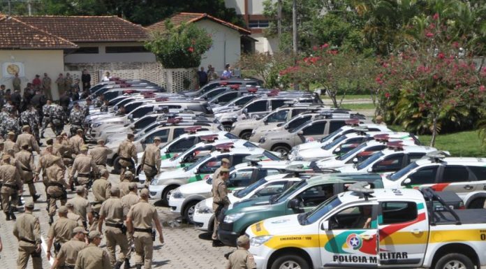 Batalhão de polícia militar anda em direção à dezenas de carros de polícia estacionados em um grande pátio para iniciar uma operação