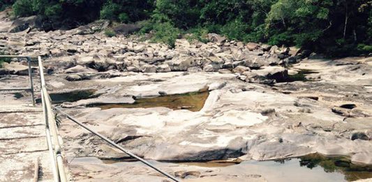 Foto do leito rochoso do rio com pouca água