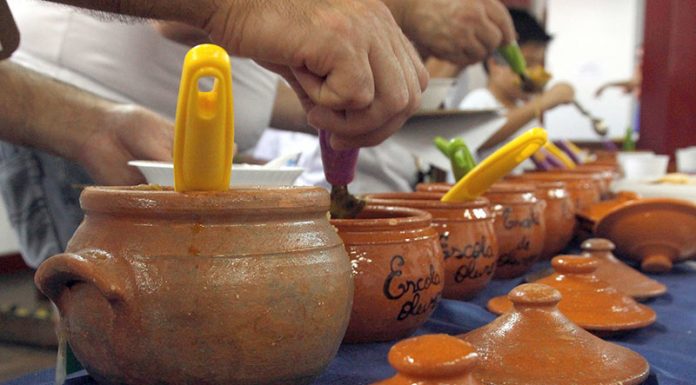 Close nos potes de barros enfileirados em que as pessoas se servem de sopa