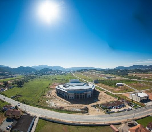 Em etapa final de construção, Arena Petry promove visitas guiadas à obra Complexo visto de cima, com rodovia passando à frente e um grande céu azul acima