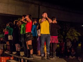 Cia. Rústica traz turnê “Cidade Proibida” para Florianópolis Grupo de atores em pé sobre uma mesa preta com as mãos tapando olhos, bocas e narizes