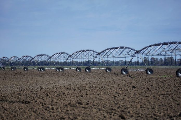 Irrigador industrial mecânico sobre uma grande lavoura de terra seca