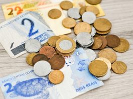Algumas notas de real e moedas espalhadas sobre a mesa
