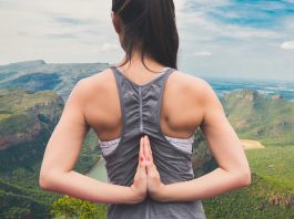 As três doenças que mais afetam as mulheres Imagem de uma mulher jovem de costas, com as mãos colocadas para trás em forma de oração; ao fundo, uma paisagem de montanhas