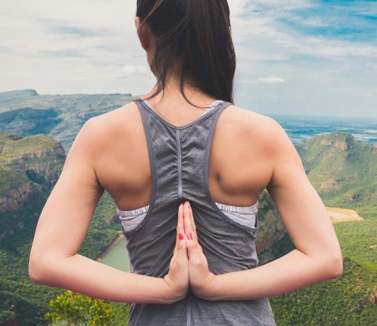 As três doenças que mais afetam as mulheres Imagem de uma mulher jovem de costas, com as mãos colocadas para trás em forma de oração; ao fundo, uma paisagem de montanhas