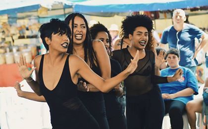 Quatro mulheres negras, usando roupas pretas, em apresentação