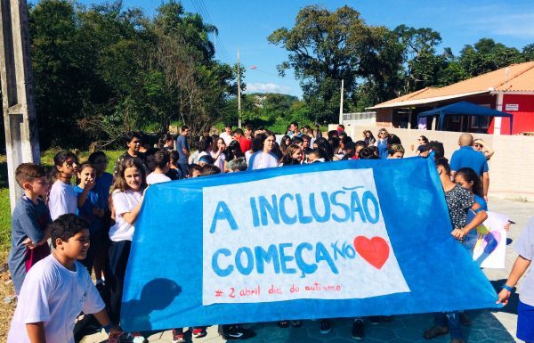 Com uma faixa à frente escrita "a inclusão começa no coração", alunos fazem passeata