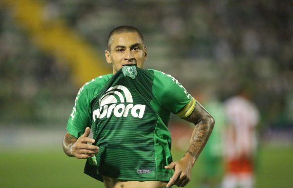Jogador Wellington Paulista corre em campo com o brasão da camisa na boca