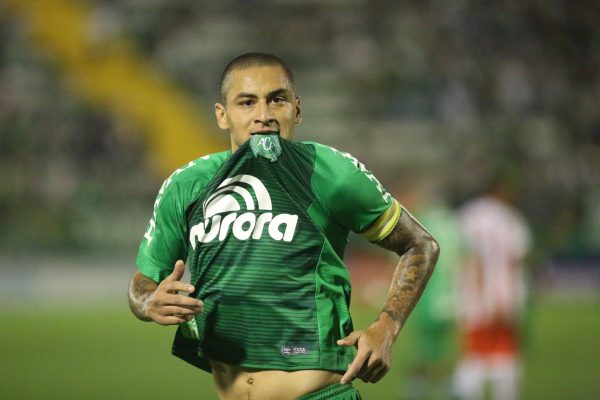 Jogador Wellington Paulista corre em campo com o brasão da camisa na boca