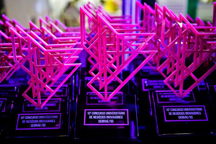 Concurso universitário Sebrae-SC Troféus da edição anterior dispostos sobre uma mesa