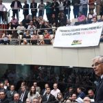 Governador Pinho Moreira fotografado de lado discursando para a assembleia lotada