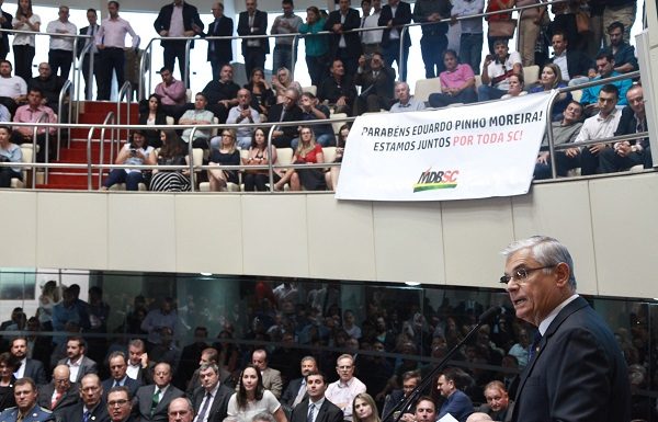 Governador Pinho Moreira fotografado de lado discursando para a assembleia lotada