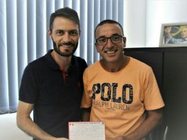 Protetor dos animais no PDT Dois homens posam para foto segurando a ficha de filiação de reni (à direita), usando camiseta laranja óculos; os dois estão no gabinete