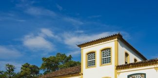 Imagem da fachada do museu; construção estilo açoriana: paredes em branco com janelas verdes