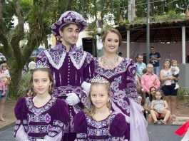 quatro pessoas (homem, mulher , menino e menina) vestidos de forma igual com trajes imperiais roxos sorridentes para a foto