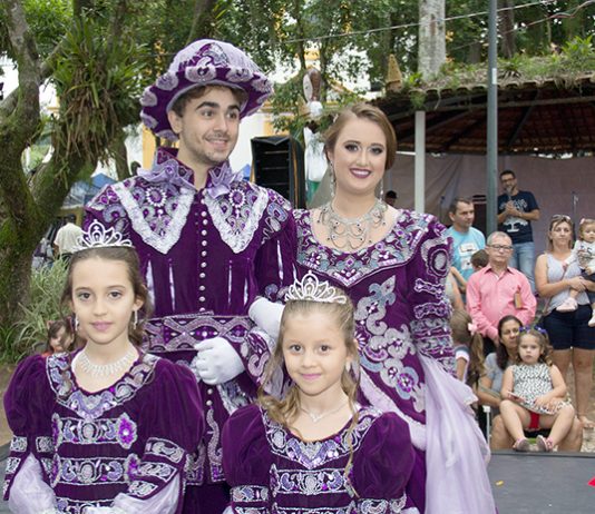 quatro pessoas (homem, mulher , menino e menina) vestidos de forma igual com trajes imperiais roxos sorridentes para a foto