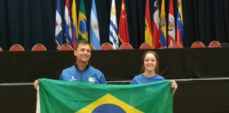 Homem e moça seguram a bandeira do Brasil