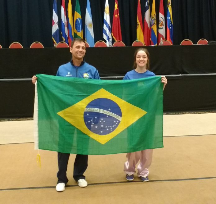 Homem e moça seguram a bandeira do Brasil