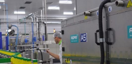 Fábricas regionais de refrigerantes sofrem com desigualdade tributária equipamentos de uma fábrica com um funcionário inspecionando garrafas em linha