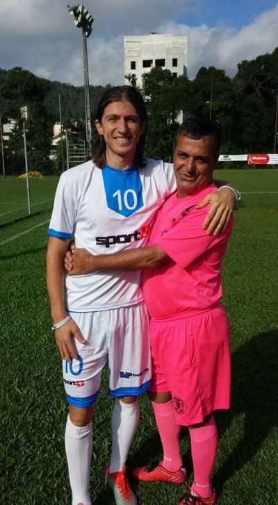 jogador filipe luis com uniforme de treino posa abraçado com o árbitro margarida, ambos sorriem