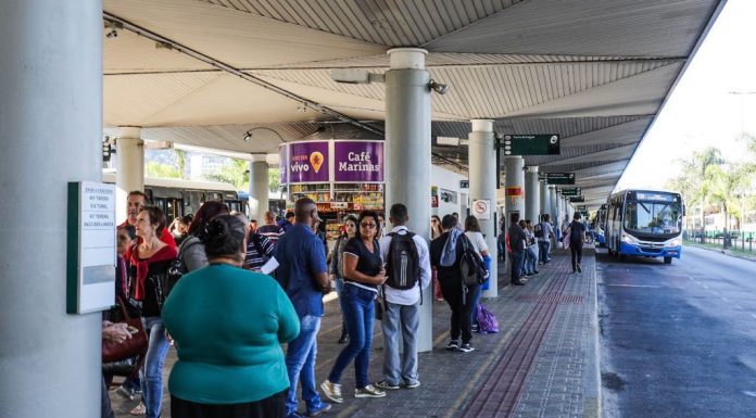 pessoas esperando ônibus em plataforma de terminal