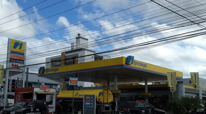 posto de combustível com caminhão tanque e duas caminhonetes da polícia civil