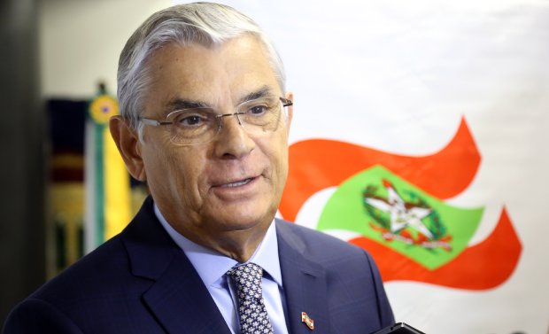 Governador de Santa Catarina Eduardo Pinho Moreira posa para foto em frente a bandeira do estado