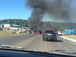 carro parado sobre a rodovia e à frente fumaça preta
