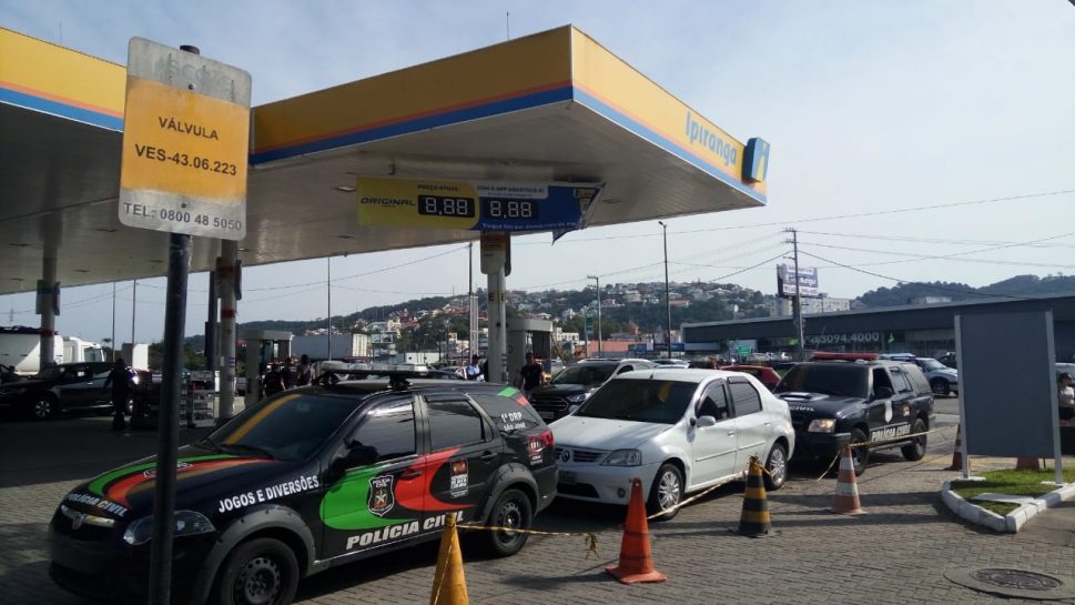 Carros da polícia civil estacionados em um posto de gasolina