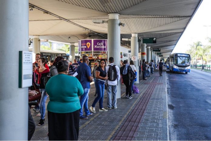 ticen - cristiano andujar - pmf (2) pessoas esperam ônibus em plataforma
