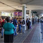 pessoas esperam ônibus em plataforma