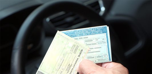 STJ autoriza suspensão da carteira de motorista de devedor duas carteiras de motoristas seguradas por uma mão com o interior de um carro ao fundo