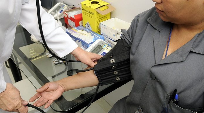 profissional mede a pressão no braço de uma paciente