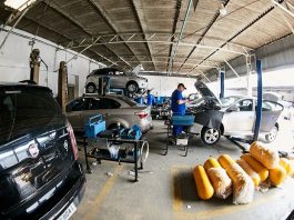 Carros em oficina com mecânico no meio e vários cilindros de gnv