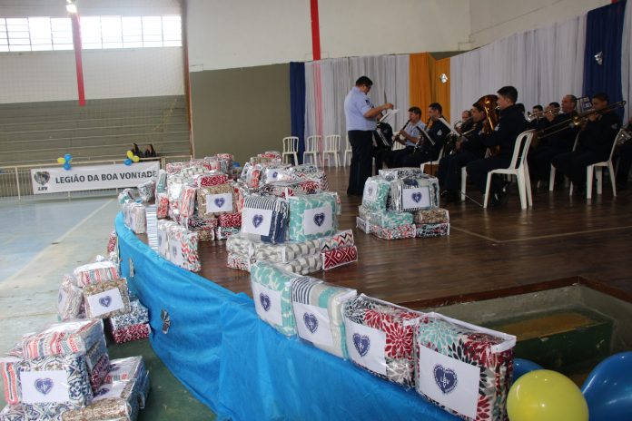 lb centrega 300 cobertores em sao jose pacotes de cobertores com o logo da LBV dispostos sobre um palco onde toca a banda, regida por um maestro