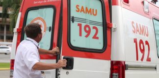 Homem abre a porta traseira direita de uma ambulância do samu estacionada na rua