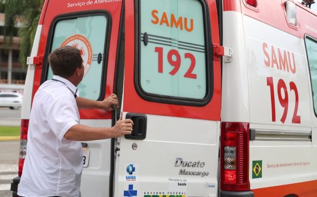 Homem abre a porta traseira direita de uma ambulância do samu estacionada na rua