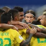 Jogadores da seleção, usando uniforme, se abraçam em grupo