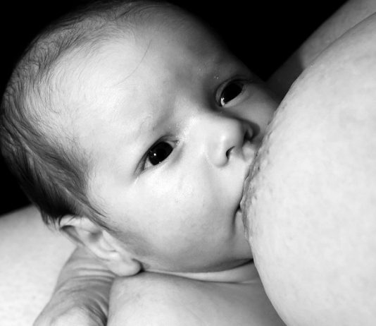 foto em preto e branco de um recém nascido mamando em um seio